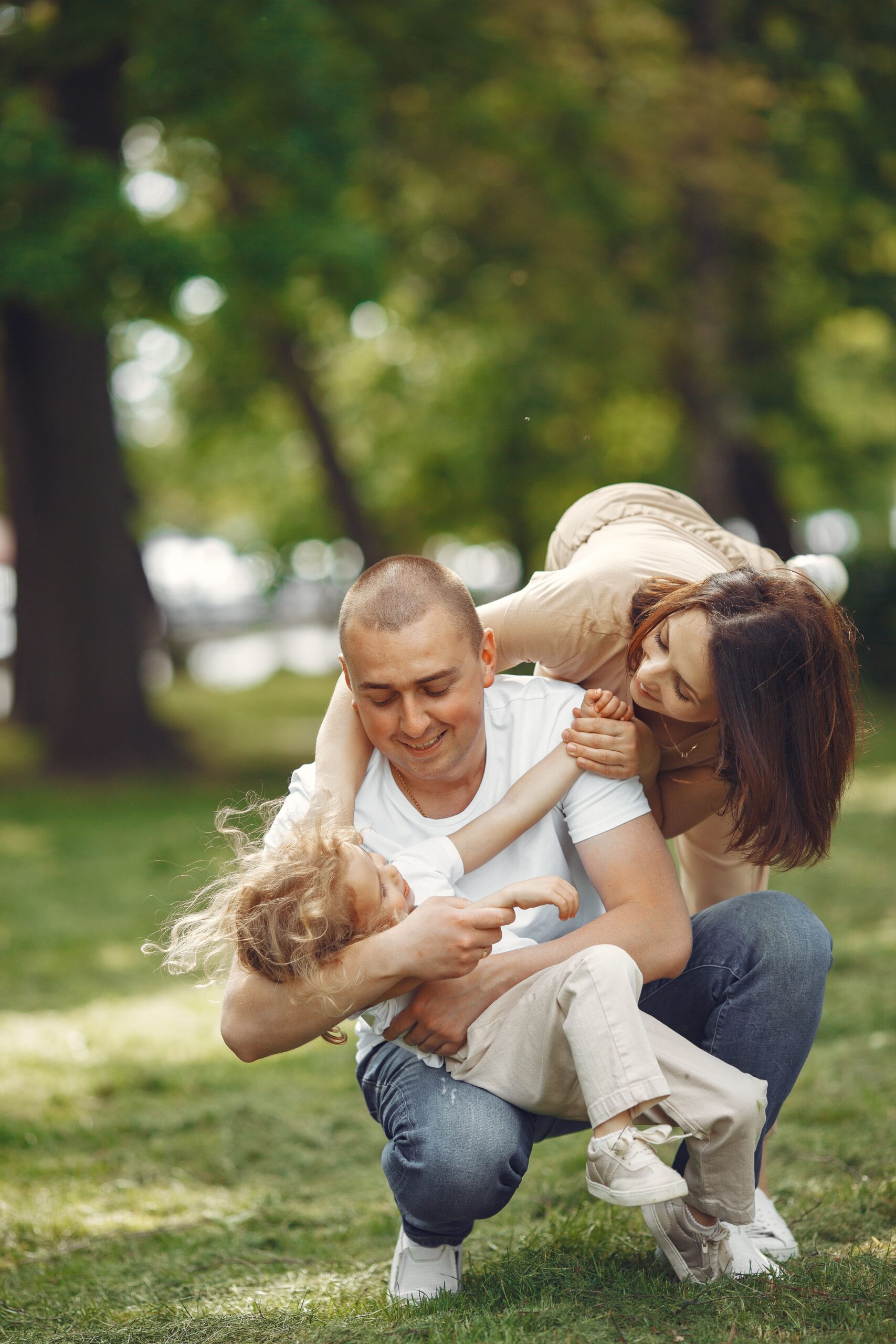 A joyful family playing together in a sunny park, embracing love and connection.